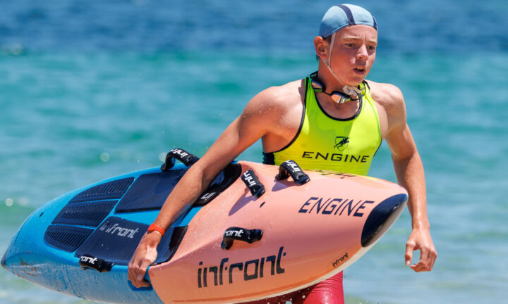 Surf lifesaver carrying a paddle board out of the sea